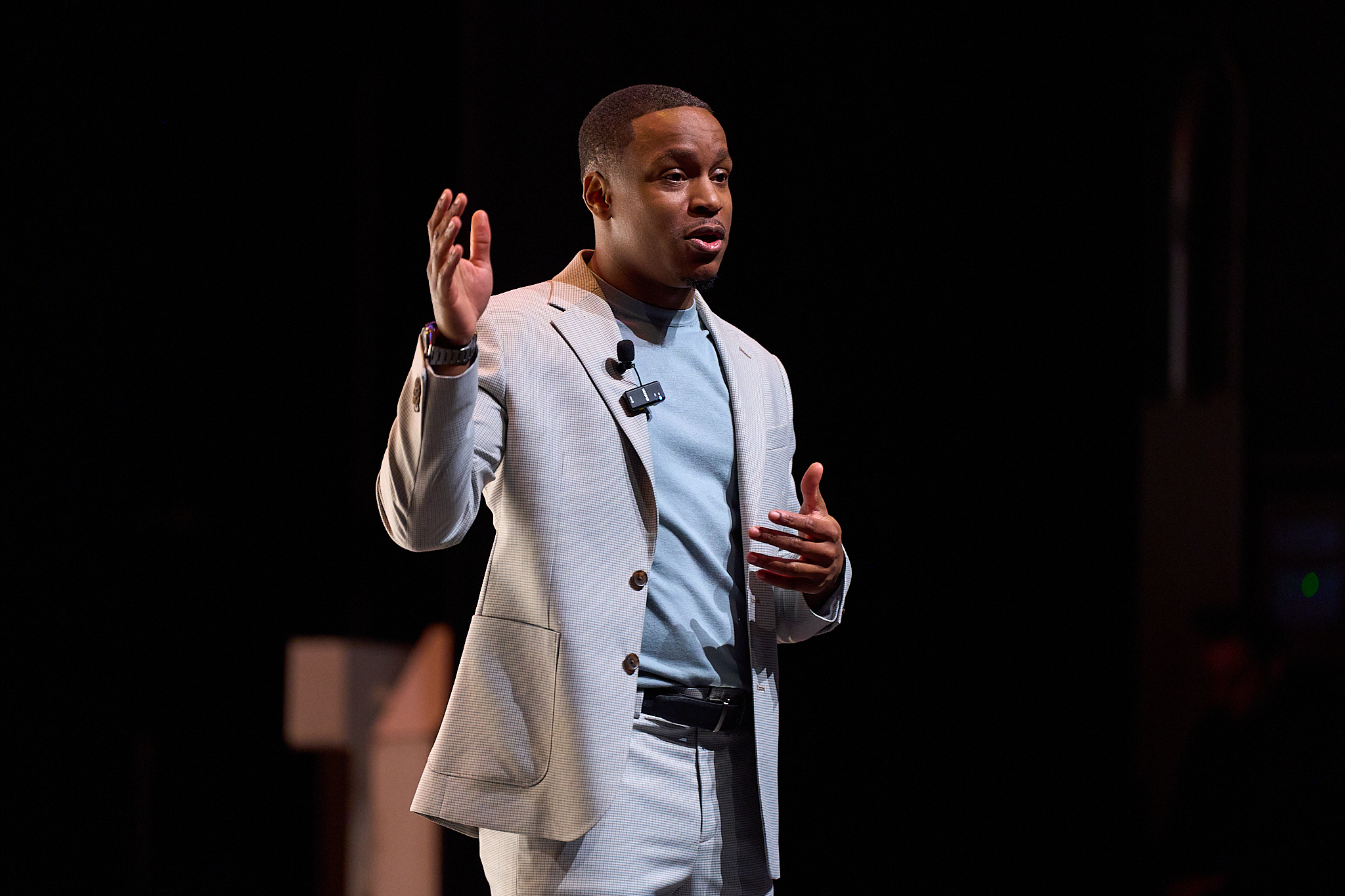 Jamyle Cannon mid-speech with both hands raised on stage